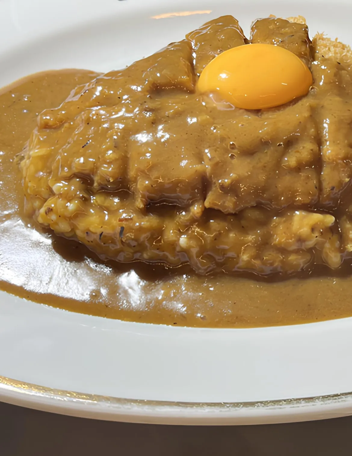 上等カレーの看板メニュー、生卵をのせた甘辛カツカレー